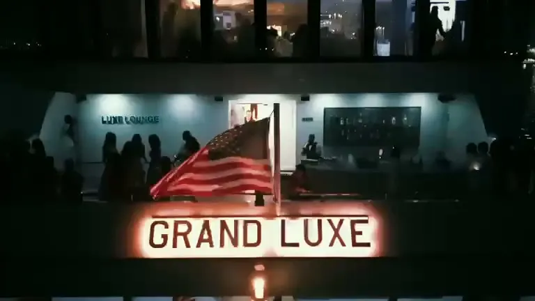 The Grand Luxe sign glowing on the yacht's deck at night.